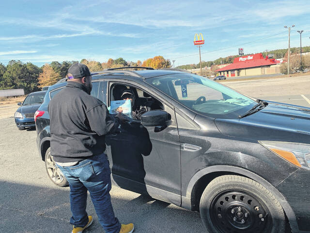 A volunteer hands out a food box and eggs.
Hannah Barron | Anson Record