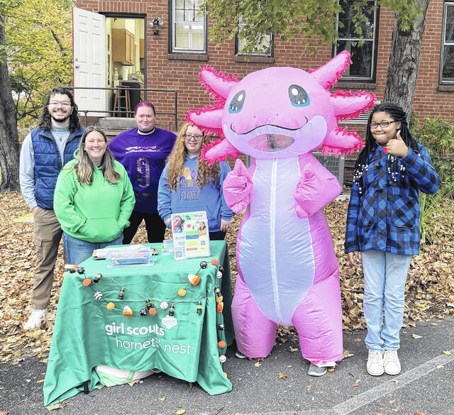 Caleb Lanye (troop co-leader), Melody Thompson (Council Representaive), Cynthia Hassell (troop product manager), Cheyenne Hassell and Zamya Chambers (Girl Scouts) pictured with Ace Rosada, this years troopcookie sale mascot, Axolotl (manned by Jessica Laney).
                                 Photo courtesy of Laura Laney