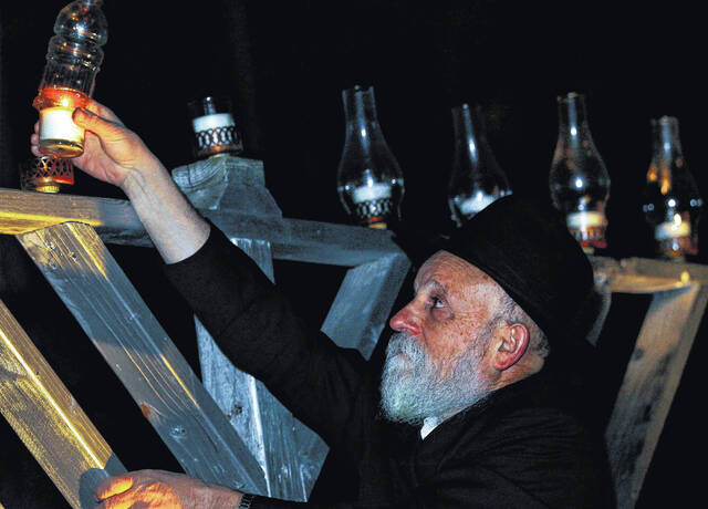 Rabbi Tzvi Perlman lights the menorah (File photo)