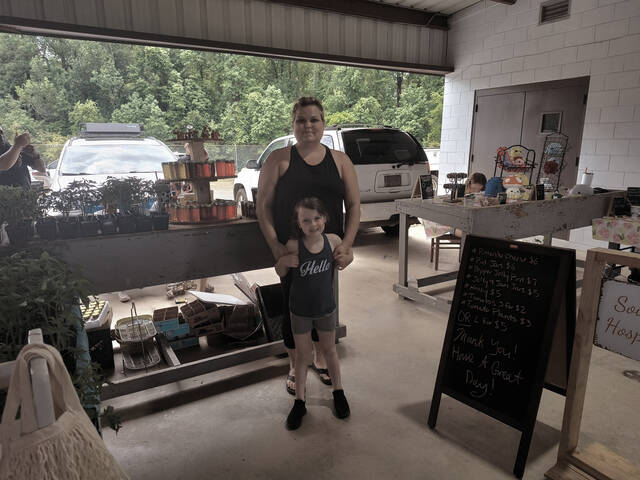 Allyce Brown of Southern Hospitality takes a pause from the Saturday sales rush to pose with little Phoenix Hough